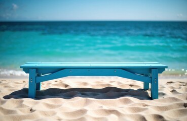 A blue wooden bench sits on a sandy beach with the ocean and clear sky in the background