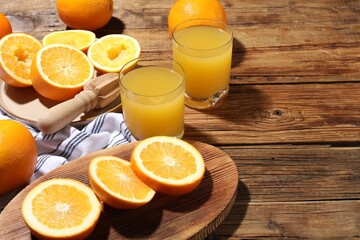 Freshly squeezed orange juice, fruits and juicer on wooden table, closeup. Space for text