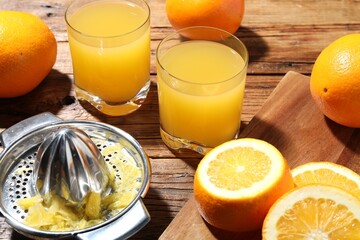 Freshly squeezed orange juice, fruits and juicer on wooden table, closeup