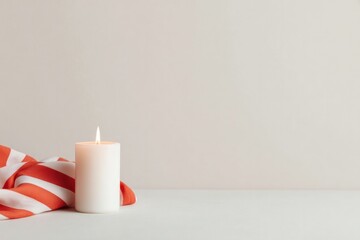 Candle on clean surface next to striped cloth, creating serene atmosphere