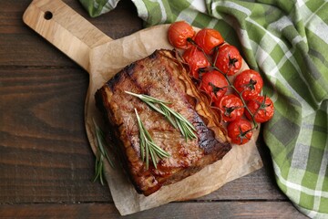 Delicious roast beef with rosemary and tomatoes on wooden table, top view
