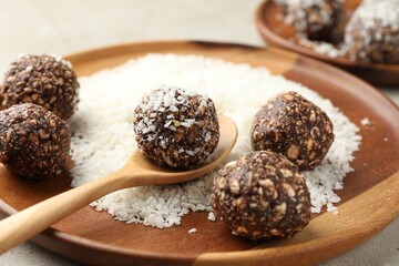 Making tasty chocolate candies with nuts and coconut flakes at light table, closeup