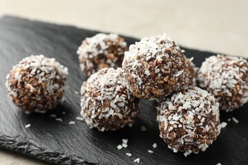 Tasty chocolate candies with nuts and coconut flakes on light table, closeup