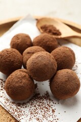 Tasty chocolate candies with cocoa powder on light table, closeup