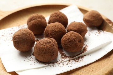 Tasty chocolate candies with cocoa powder on light table, closeup