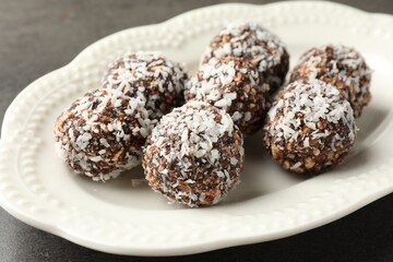 Tasty chocolate candies with nuts and coconut flakes on grey table, closeup