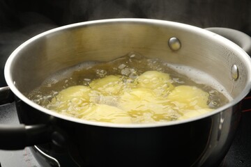 Young potatoes boiling in pot on stove, closeup