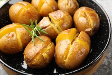 Tasty baked potatoes with rosemary served on light grey table, closeup