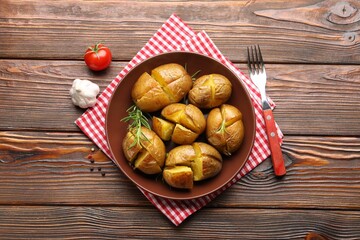 Tasty baked potatoes with rosemary served on wooden table, flat lay