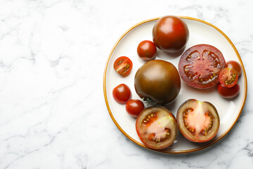 Whole and cut brown tomatoes on white marble table, top view. Space for text
