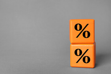 Percent signs on orange cubes against grey background. Space for text