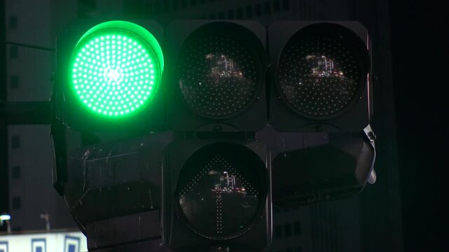 TOKYO, JAPAN - AUG 2025 : Close up shot of led traffic light at the street in night time. Green, yellow, red and arrow. Japanese traffic and transportation concept 4K video.
