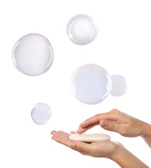 Woman washing hands with soap bar on white background, closeup. Bubbles flying around