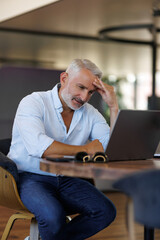 Stressed office worker sitting at desk with laptop feeling burnout. Man looking frustrated while...