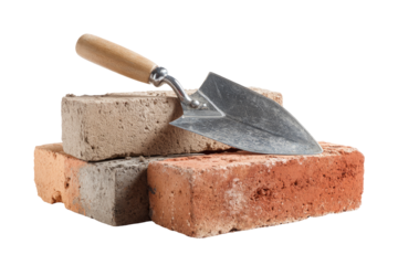 Stacked bricks with trowel.  Wooden handle trowel rests atop two bricks, one light tan, one reddish-brown.  Studio shot, isolated
