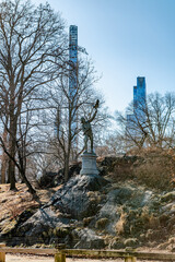 Central Park statue, skyline view. A bronze statue stands atop a rock in Central Park, framed by...