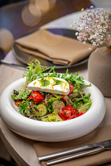 Cheese veggie salad served. Colorful salad with lettuce, tomatoes, cucumbers, and cheese presented on a table with decor and soft lighting.