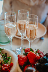Festive brunch with bubbly. Three glasses of sparkling drink sit alongside a fresh salad and colorful berries, creating a vibrant brunch atmosphere.