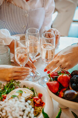 Celebration with drinks and fresh food. Friends clink sparkling drinks while enjoying a fresh salad and berries at a festive gathering in a bright room.
