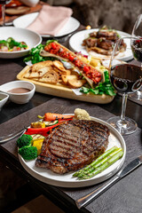 Tasty steak at a cozy spot. Succulent grilled steak served with vegetables and red wine in an inviting dining atmosphere during dinner time.