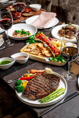 Cozy steak and wine spot. Guests enjoy gourmet steaks paired with fine wines on a tabletop filled with vibrant sides and appetizers.