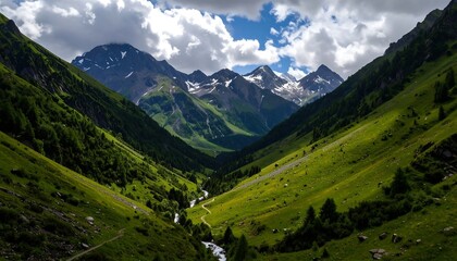 Naklejka premium Lush green valley with winding river, leading to snow-capped peaks under a bright blue sky