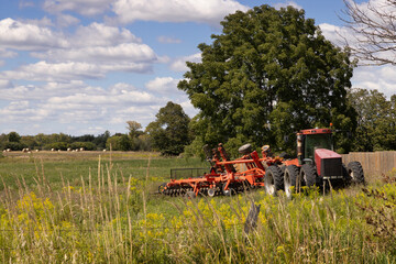 Fototapeta premium Large farming tractor with disc harrow attached for soil cultivation and preparation in rural southern Ontario Canada