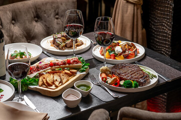 Gourmet fine dining experience. Guests savor a stylish steak meal with appetizers and red wine in a cozy restaurant.