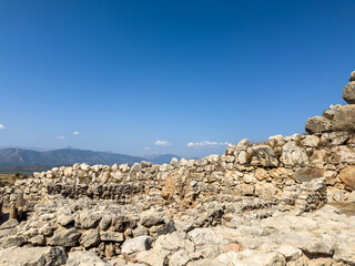 Ancient wall stone ruins at the archaeological site of Mycenae within Greece, under the clear blue...