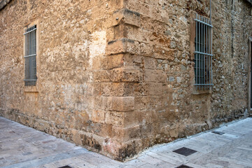 Historic building on a narrow paved street in Nafplio Greece with stone walls and barred windows