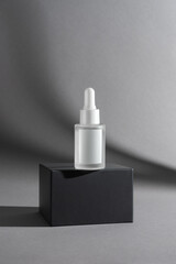 Frosted Glass Dropper Bottle on Black Box with Grey Background for Mockup
