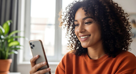 Smiling woman with curly hair looking at her smartphone indoors