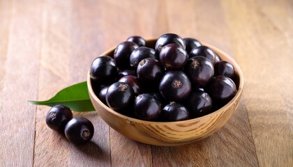 jaboticaba berries in a bowl on a wooden surface