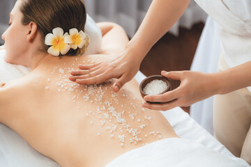 Woman customer having exfoliation treatment in luxury spa salon with warmth candle light ambient....