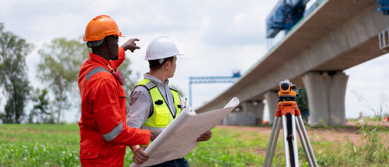 Surveyors and civil engineers using a theodolite and road construction plans to measure and inspect...