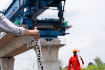 Surveyors and civil engineers using a theodolite and road construction plans to measure and inspect during the building process.
