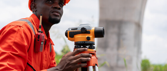 Surveyors and civil engineers using a theodolite and road construction plans to measure and inspect...