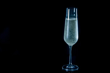 A glass of champagne is sitting on a black table