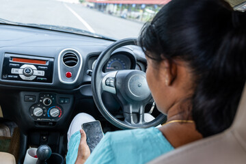 Woman using smartphone inside parked car on a sunny day