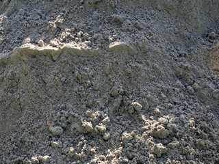 Pile of soil with natural rough texture in gray-brown colors