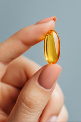 close-up of a woman's hand holding an fish oil capsule. 