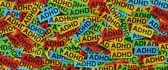 Strips of colorful paper with the abbreviation ADHD typed on them. Close up.