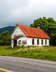 Fototapeta premium Old weathered church with rusty red roof on a country road