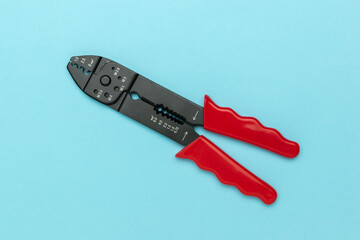 Red-Handled Wire Stripper and Crimper Tool on Blue Background: Modern Stock Photo for Tool and DIY Projects