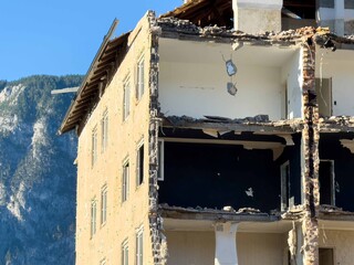 Partially demolished building with mountain backdrop