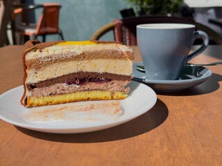 Delicious layered cake slice with coffee cup on outdoor cafe table