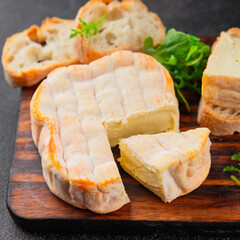 Washed rind cheese soft cheese with orange rind munster french cheese tasty snack fresh delicious gourmet food background on the table rustic top view copy space
