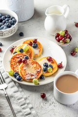 Cottage cheese pancakes with berries and condensed milk. Homemade dessert syrniki for healthy breakfast
