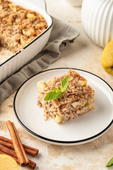 Slice of apple pie baked oatmeal in a plate on kitchen table background