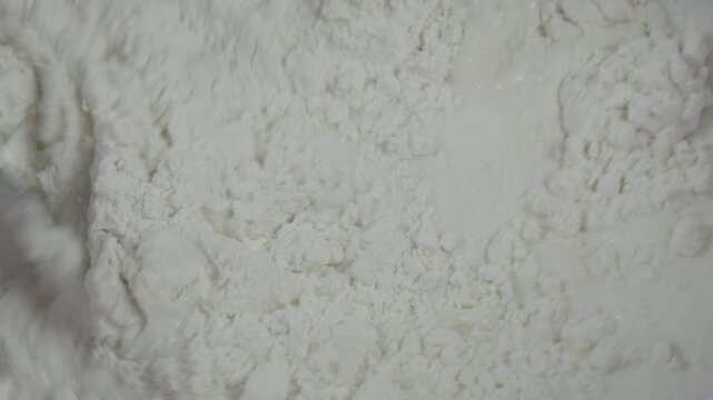 Close-up of woman preparing dough from flour, egg, and kefir in her kitchen, recorded with ambient sound.
